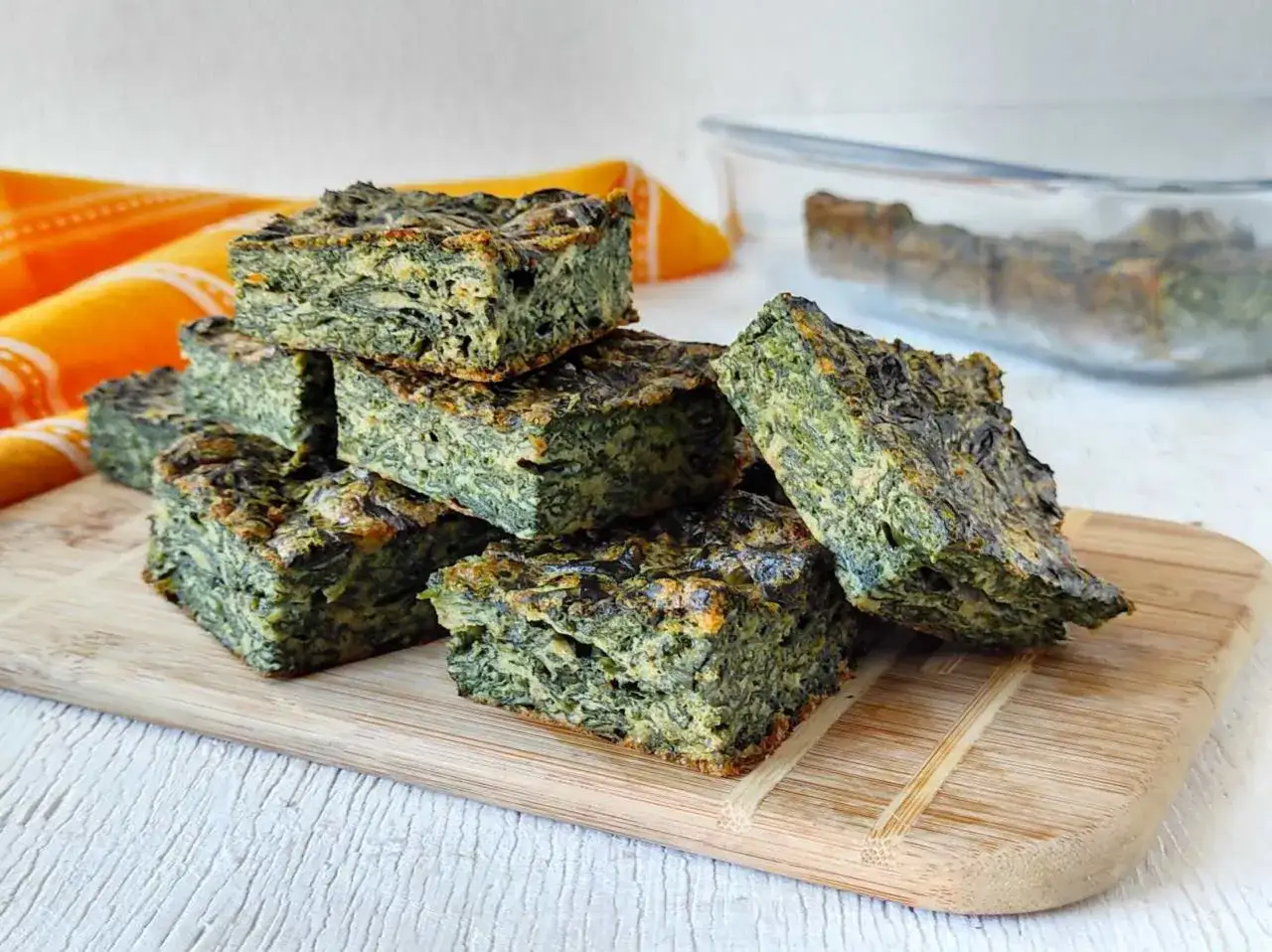 Fette di frittata di spinaci impilate su un tagliere di legno. Un piatto sano e gustoso, perfetto per un pasto leggero.