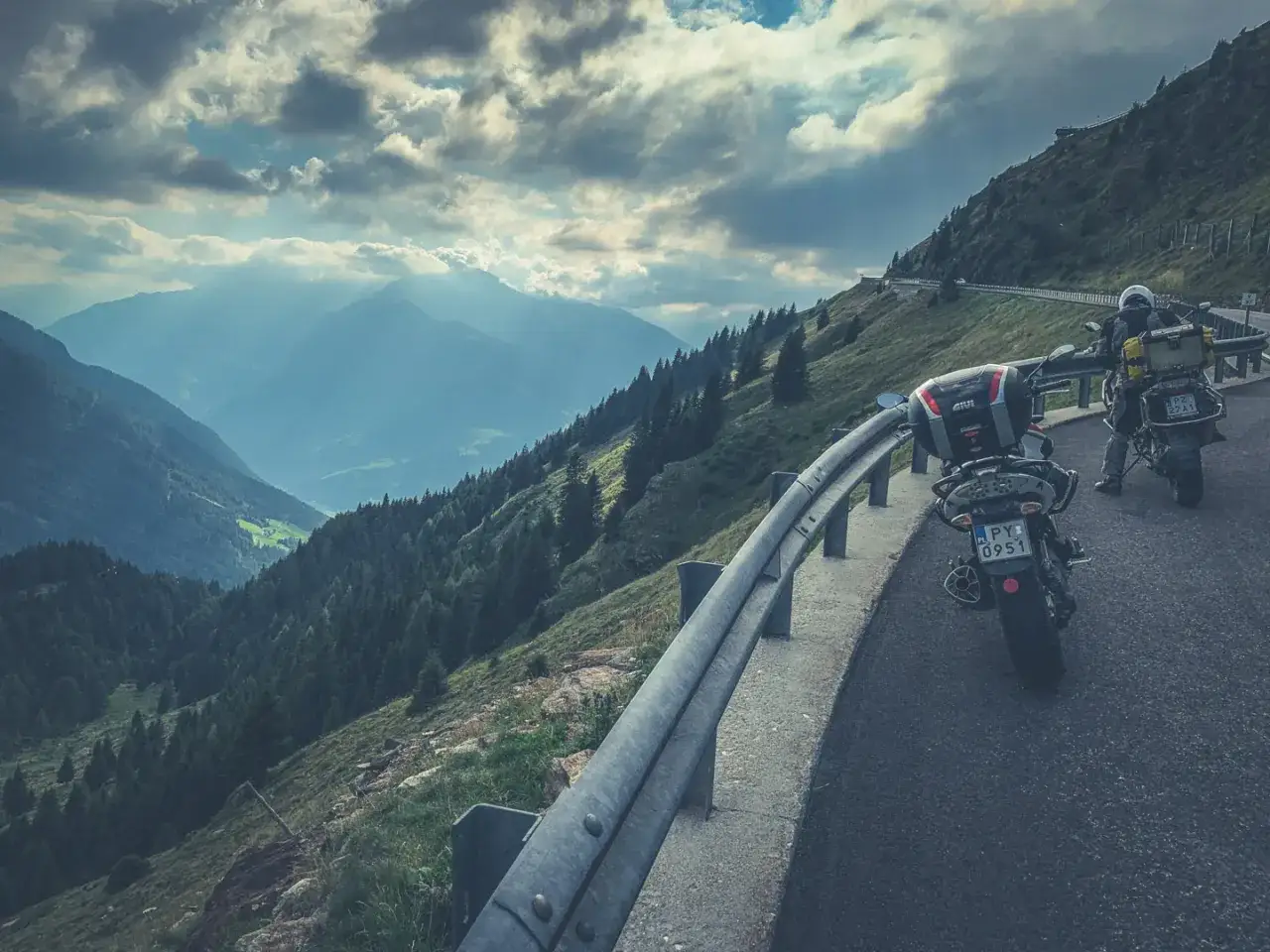 Motocykliści na krętej drodze Stelvio Pass, podziwiający majestatyczne alpejskie krajobrazy.