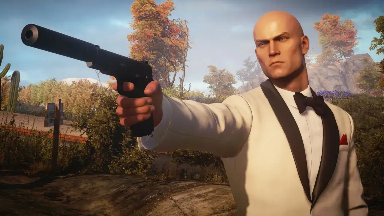 Agent 47 w białym smokingu z pistoletem, gotowy do akcji. Spolszczenie Hitman 3 sprawia, że misje są jeszcze bardziej wciągające.