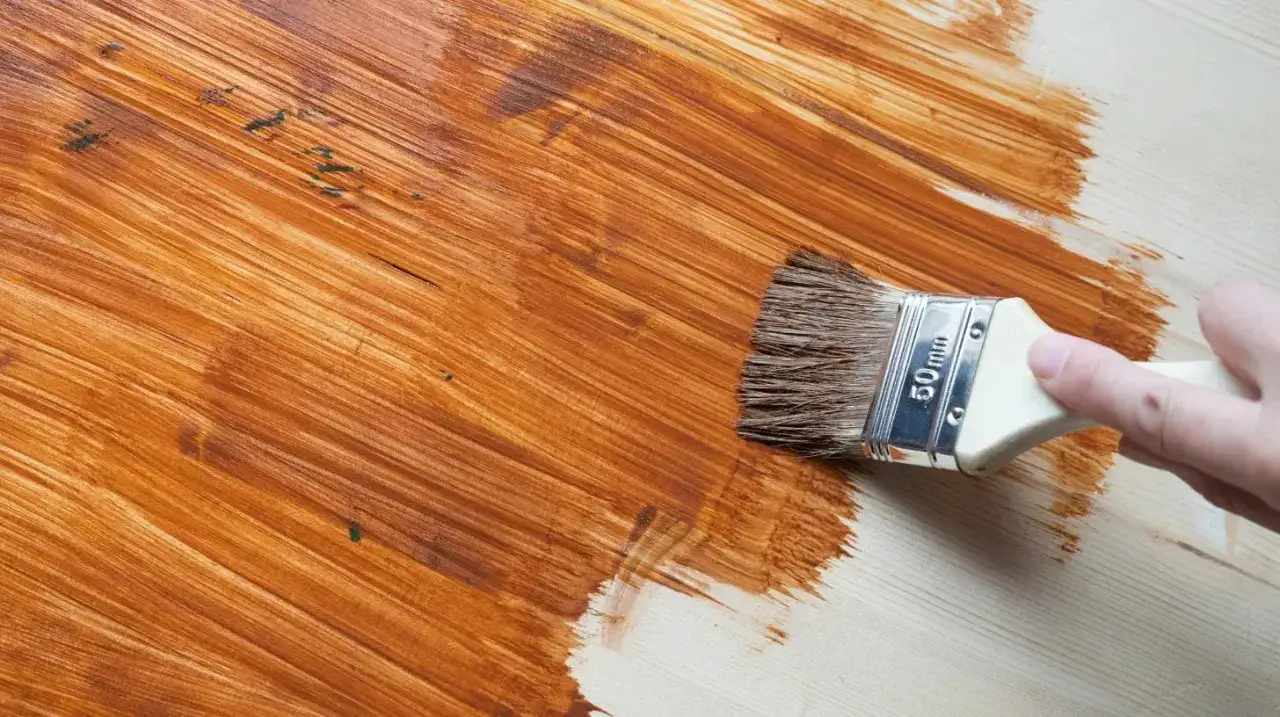 Pennello applica una mano di vernice marrone su legno chiaro. Questo &egrave; cos'&egrave; il primer per legno: prepara la superficie per una finitura perfetta.