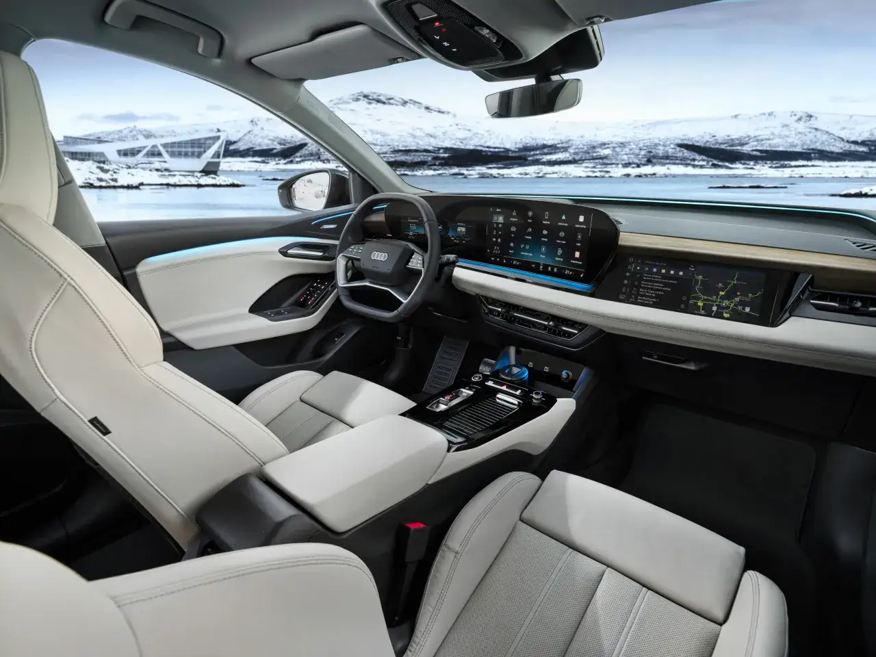 Wnętrze Audi Q6 e-tron z jasnymi skórzanymi fotelami i nowoczesnym panelem multimedialnym, za oknem zimowy krajobraz.