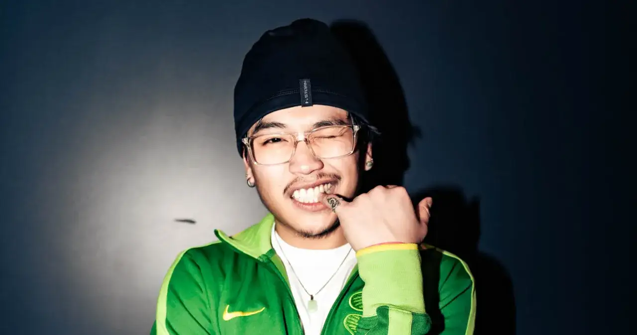 Un jeune homme avec un bonnet noir et des lunettes, clin d'œil, prêt à mixer comme un dj hip hop français.