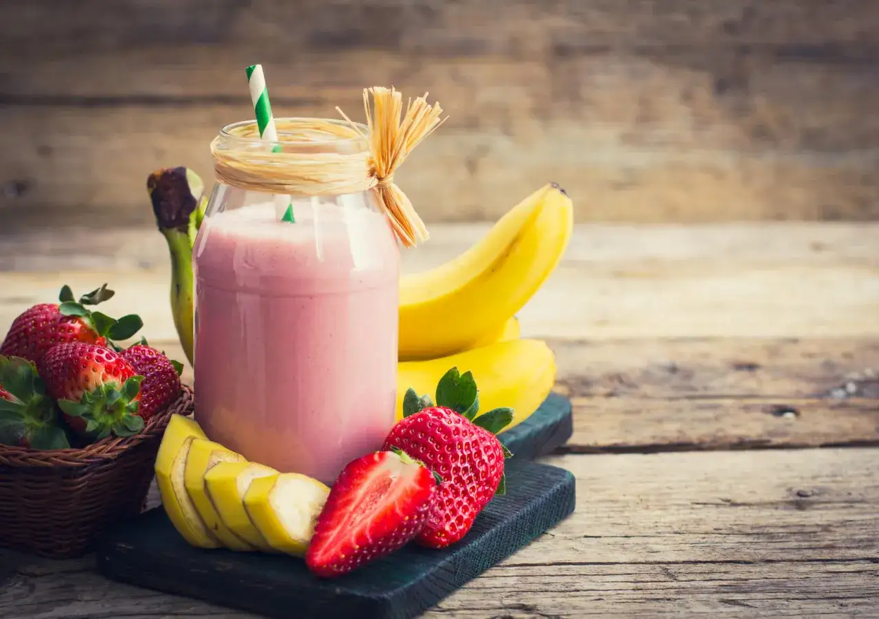 Różowy koktajl z jogurtu i owoców, z bananami i truskawkami. Zastanawiasz się, ile kalorii ma jogurt owocowy?