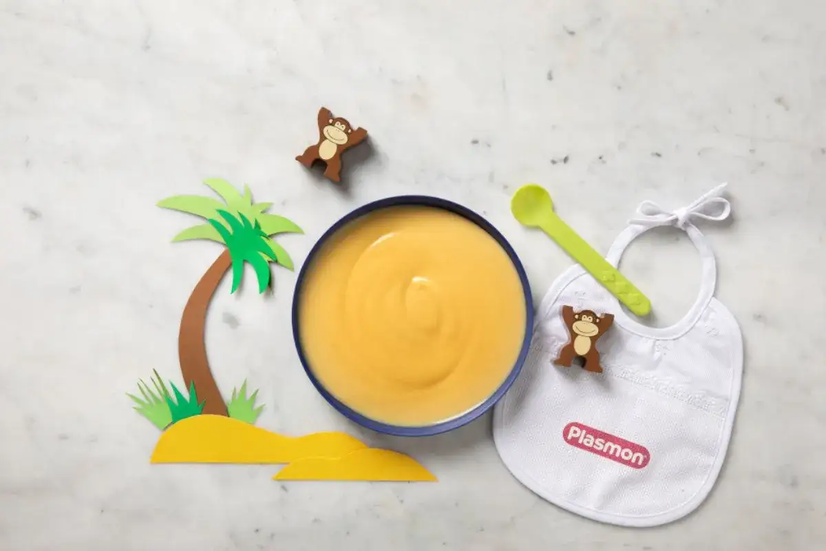Un piatto di semolino giallo, pronto per essere gustato. Un bavaglino, un cucchiaino verde e simpatici scimmiette completano la scena, suggerendo come si fa il semolino per i pi&ugrave; piccoli.