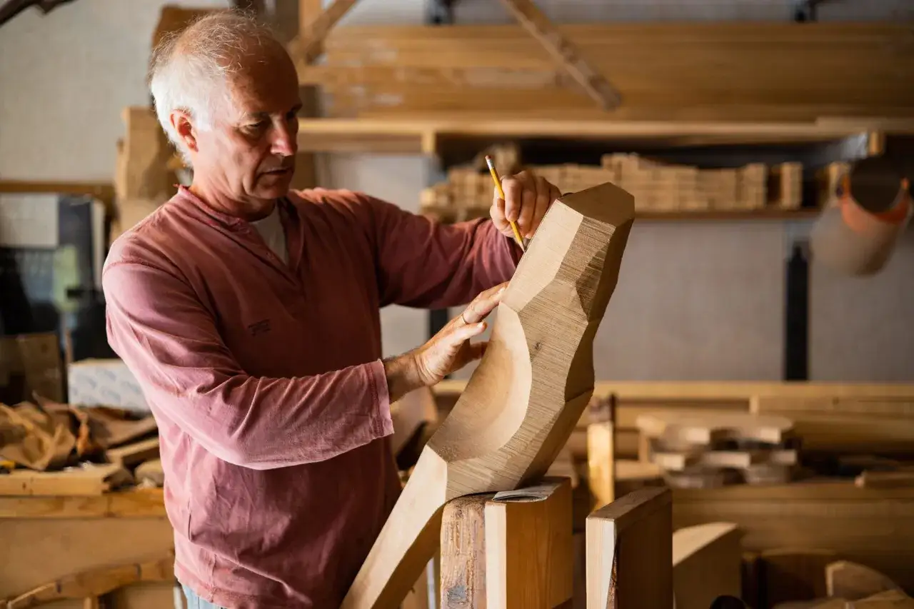 Saverio Pastor, scultore del legno, rifinisce un'opera con precisione.