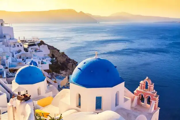 Oia Santorini białe domy niebieskie kopuły zachód słońca