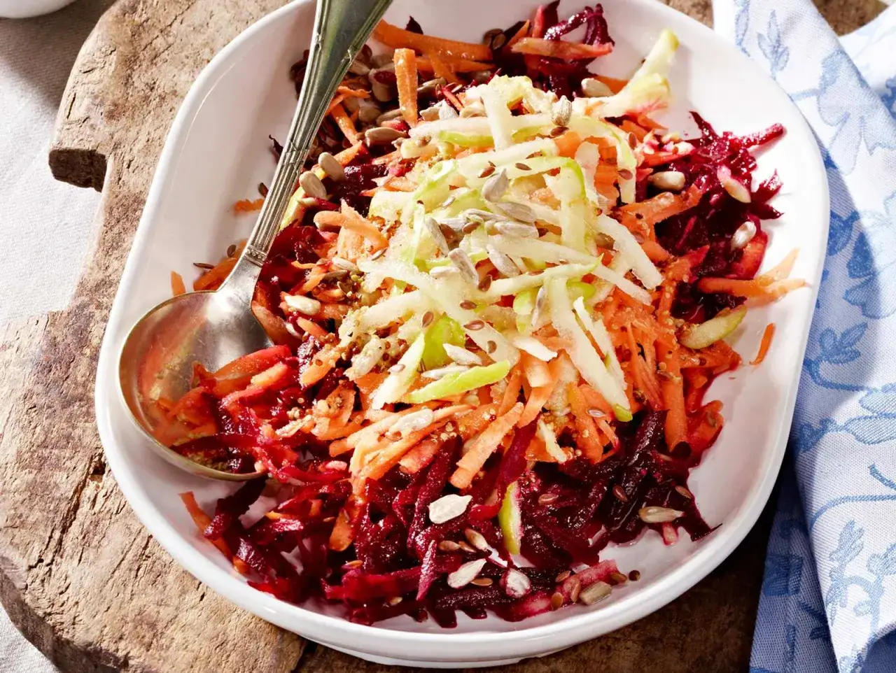 Ein bunter, traditioneller Rote Bete Salat mit geraspelten Karotten und Apfel, bestreut mit Sonnenblumenkernen.