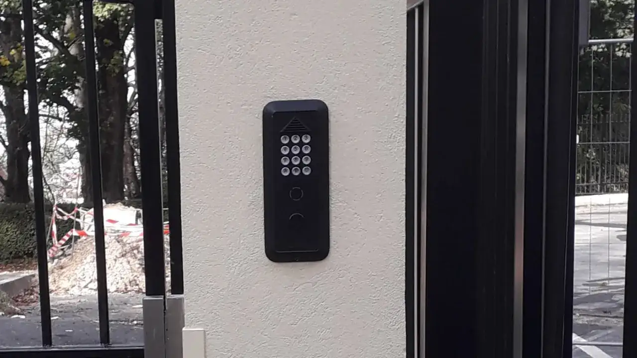 Clavier digicode noir fix&eacute; sur un mur blanc, pr&ecirc;t &agrave; commander la motorisation du portail.