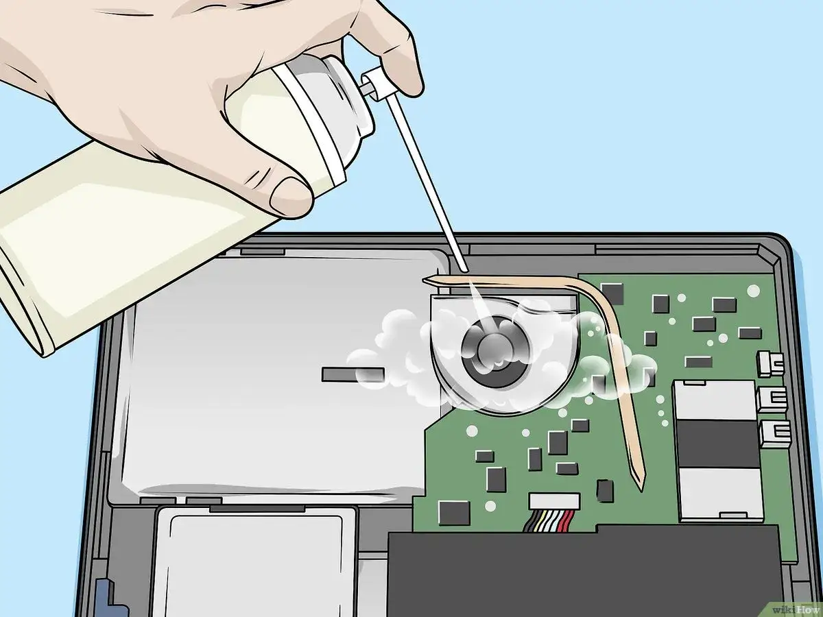 Main tenant utilise une bombe d'air comprimé pour nettoyer le ventilateur d'un pc portable.