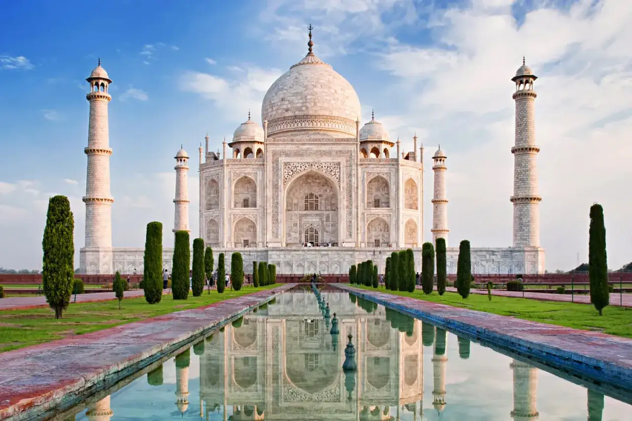 Le Taj Mahal, un des 100 plus beaux monuments du monde, se refl&egrave;te dans l'eau sous un ciel bleu.