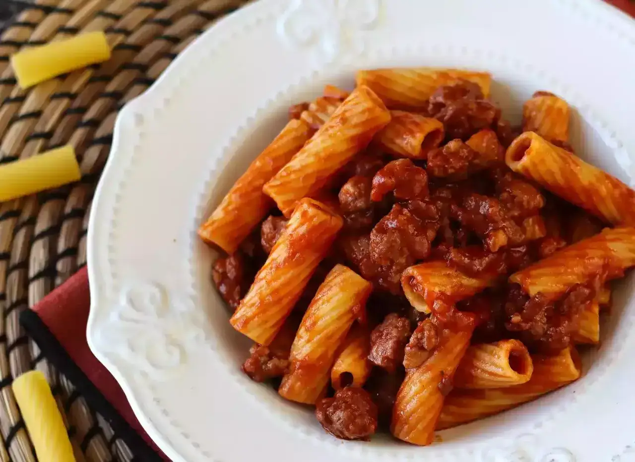 Piatto di rigatoni conditi con un saporito ragù di salsiccia, pronto per essere gustato.