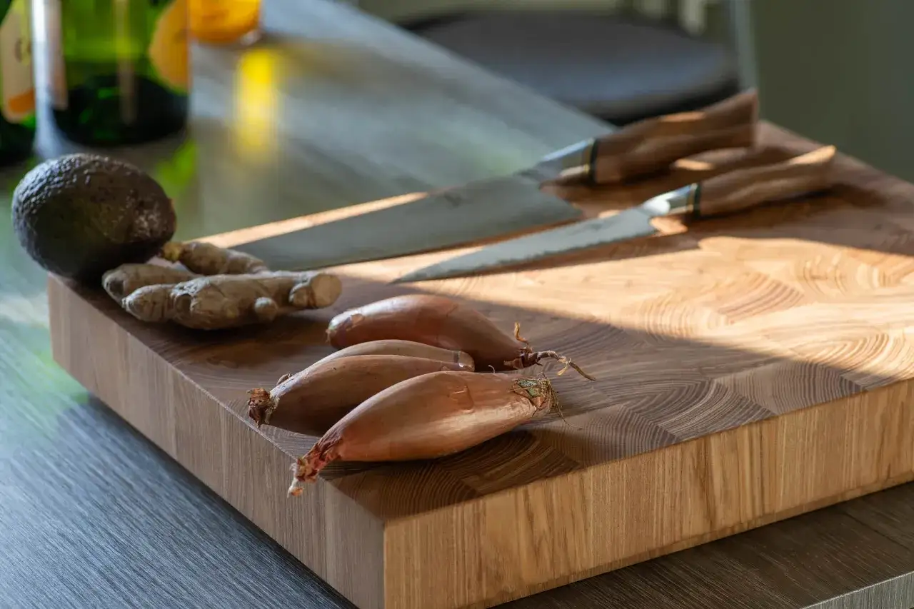 Avokado, ingefära och schalottenlök ligger på en skärbräda. Två vackra knivar, kanske den bästa kniven för jobbet, ligger redo för matlagning.