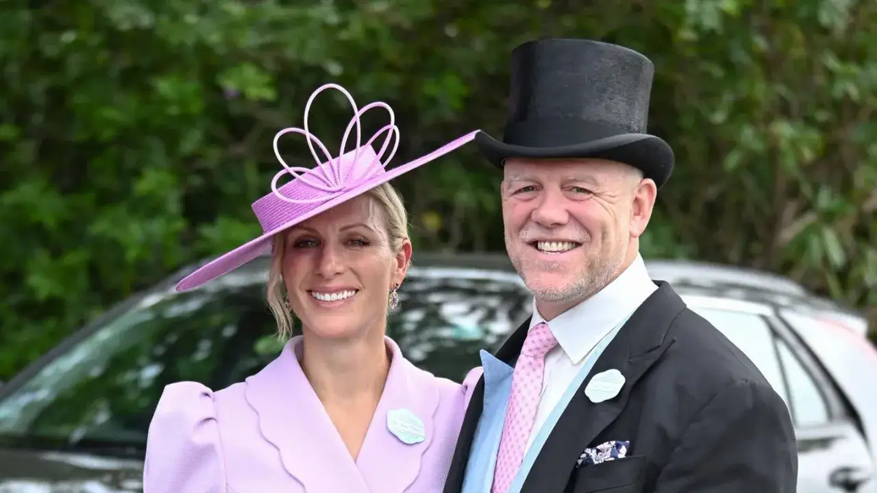 Ein Paar in festlicher Kleidung, das den Royal Ascot Dresscode befolgt. Sie tr&auml;gt einen auff&auml;lligen lila Hut, er einen Zylinder.