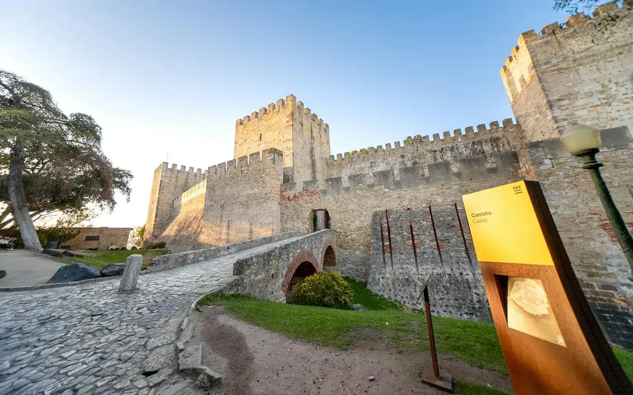 Eingang zum Castelo de S&atilde;o Jorge mit Br&uuml;cke und Schild. Tickets f&uuml;r die Burg sind hier erh&auml;ltlich.