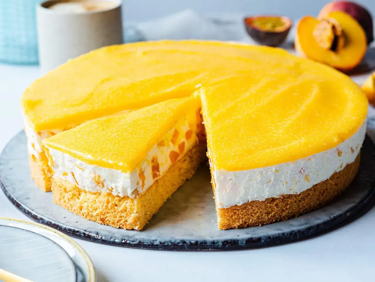 Eine saftige Pfirsich Maracuja Torte mit Biskuitboden, cremiger Füllung und fruchtigem Topping. Ein Stück ist bereits angeschnitten.