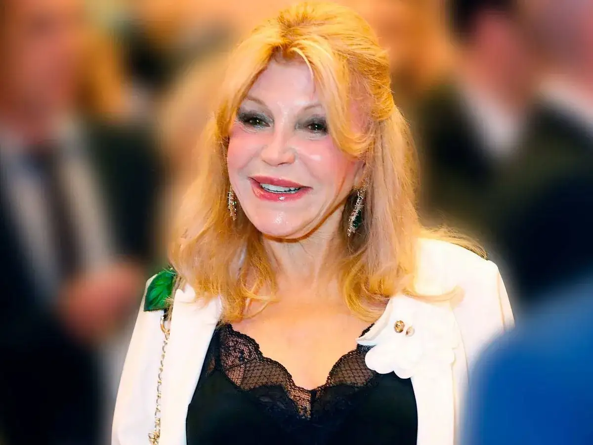 Tita Thyssen sonr&iacute;e con elegancia, luciendo un blazer blanco sobre un top de encaje negro.