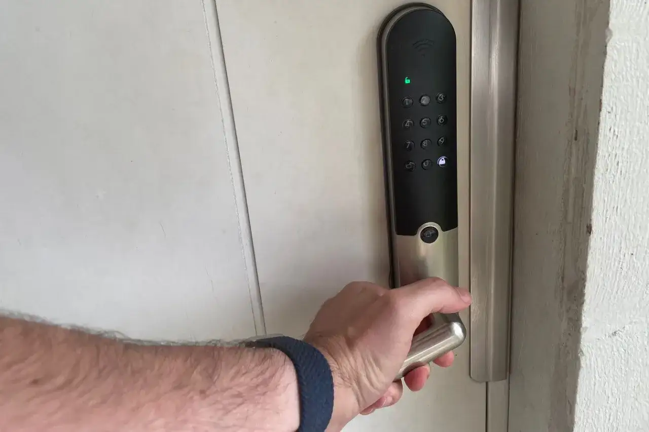 Hand griper handtaget på ett lås Yale Doorman med digital knappsats.