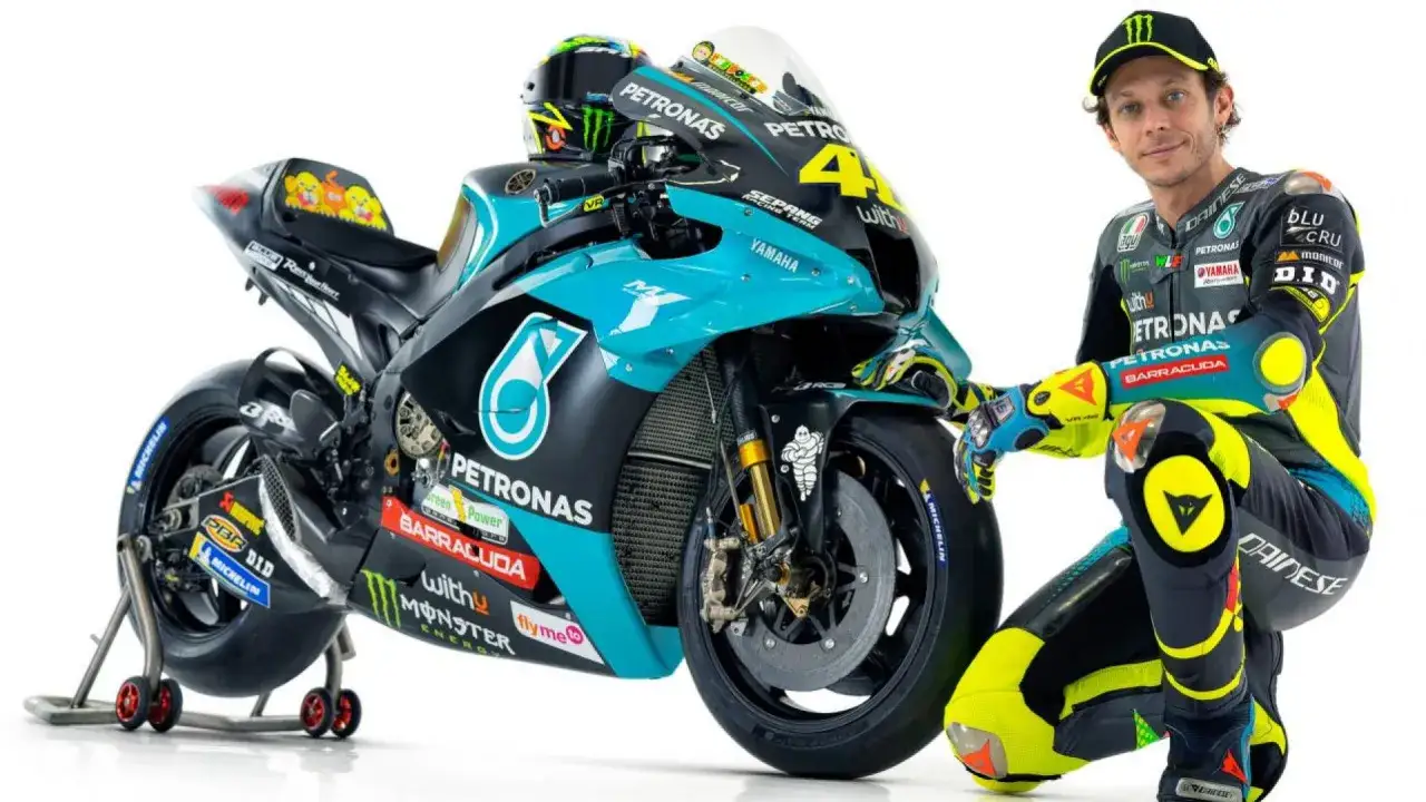 Valentino Rossi in tuta e casco, accanto alla sua moto Petronas Yamaha con il numero 46.
