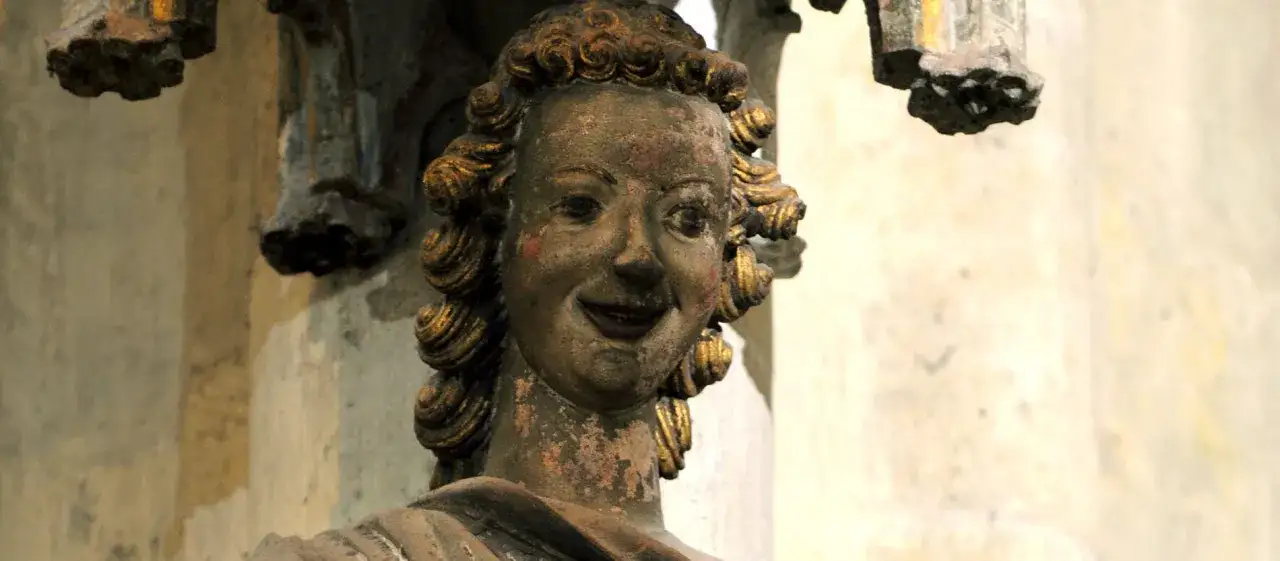 Detail einer lächelnden Figur mit goldenen Locken, eine der vielen faszinierenden Regensburger Dom Figuren, die Geschichte atmen.