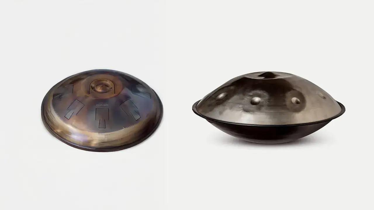 Zwei runde Metallinstrumente, Handpans, liegen nebeneinander. Eines ist bronzefarben mit eingravierten Noten, das andere silbern mit drei kleinen Höckern.