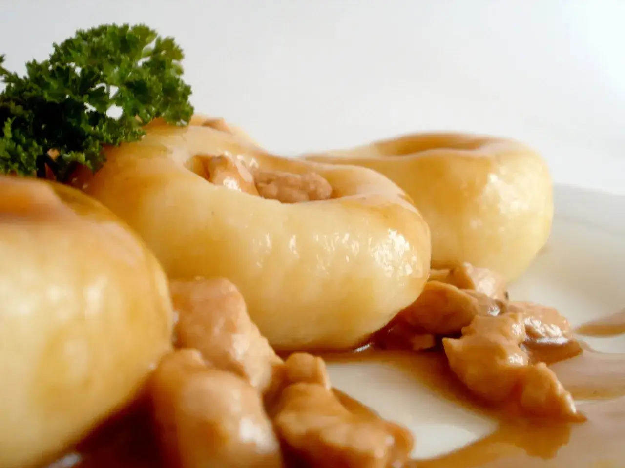 Gnocchi z kurczakiem w sosie, udekorowane natką pietruszki. Pyszne danie na talerzu.