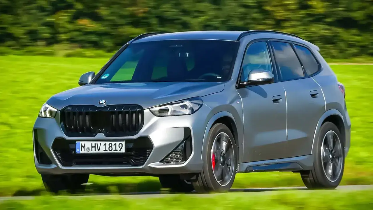 Grauer BMW X1 23d fährt auf einer grünen Wiese.