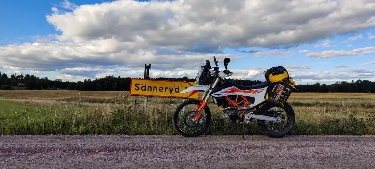 Przygoda na motocyklu w Szwecji. Motocykl KTM z bagażem przy drogowskazie Sänneryd.