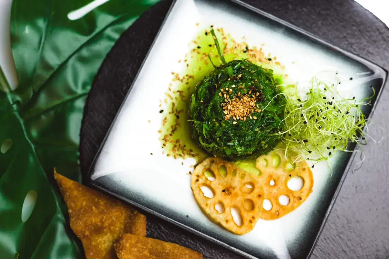 Pyszna sałatka do sushi z wodorostów wakame, posypana sezamem, z kiełkami i chipsami z lotosu.