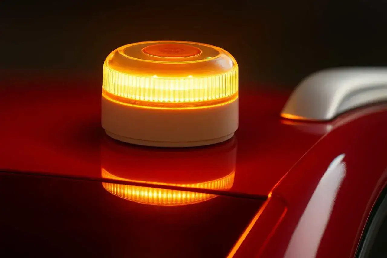 Baliza de emergencia naranja brillante sobre un coche rojo. Evita una multa con esta luz de advertencia.