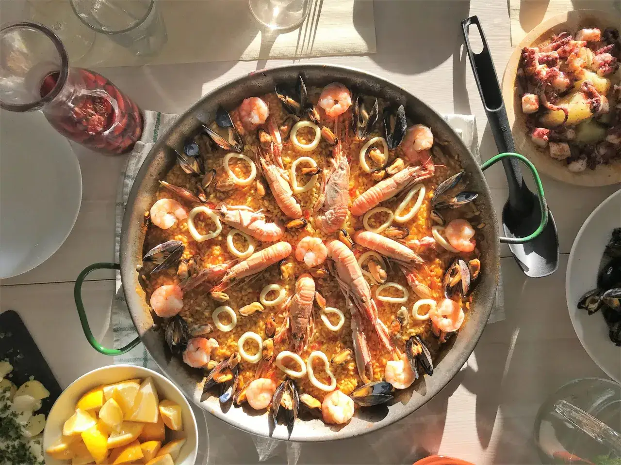 Pyszne hiszpańskie jedzenie: paella z owocami morza, krewetkami, małżami i kalmarami, podana z cytryną.