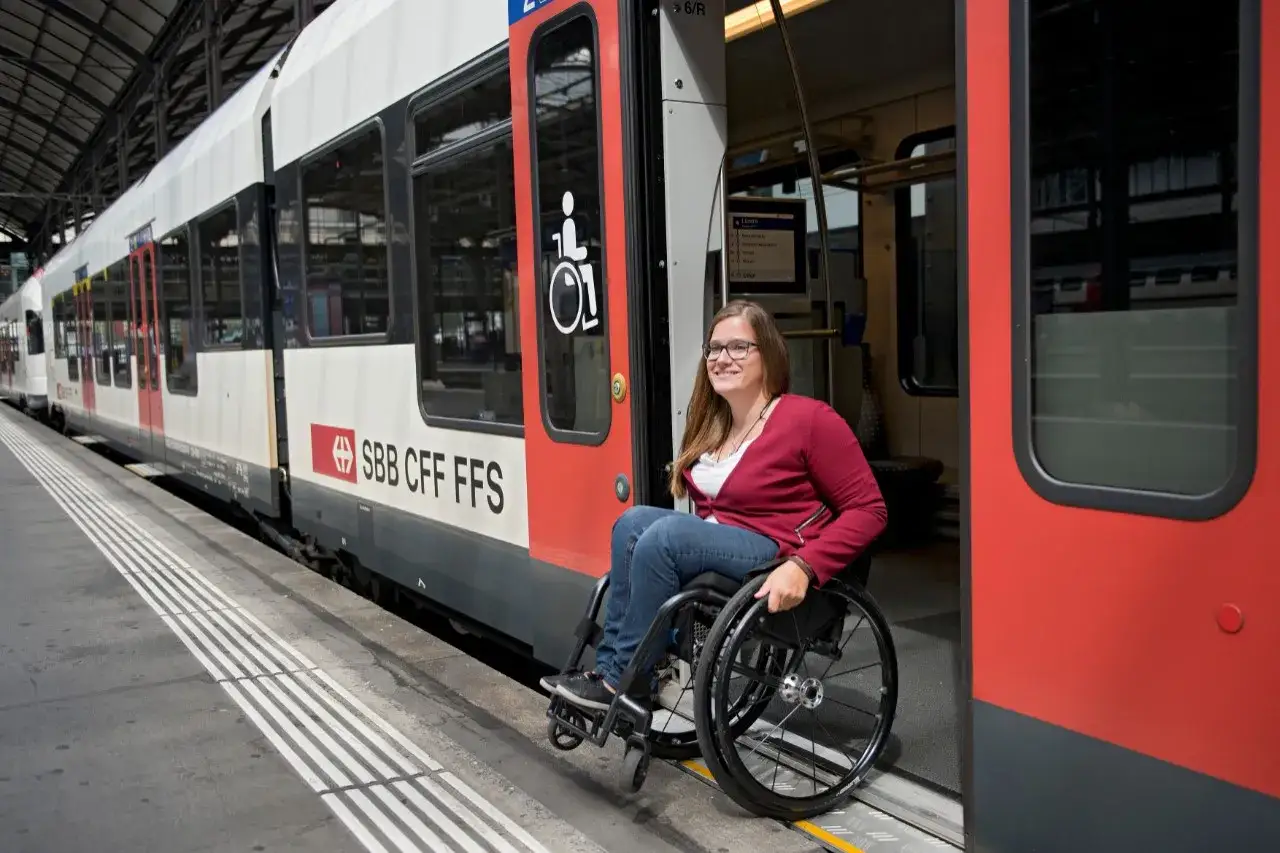 Donna in sedia a rotelle pronta per il trasporto disabile su un treno SBB CFF FFS.