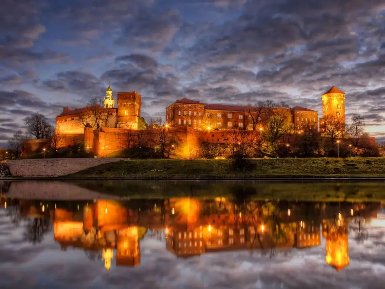 Beleuchtetes Wawel-Schloss in Krakau, ein Muss f&uuml;r Krakau-Sightseeing, spiegelt sich im Fluss.