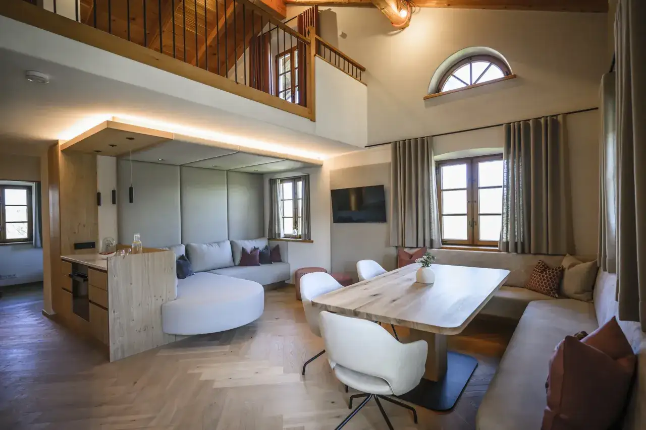 Gemütliche Einrichtung einer Ferienwohnung mit Holzboden, bequemer Couch, Essbereich und Galerie.
