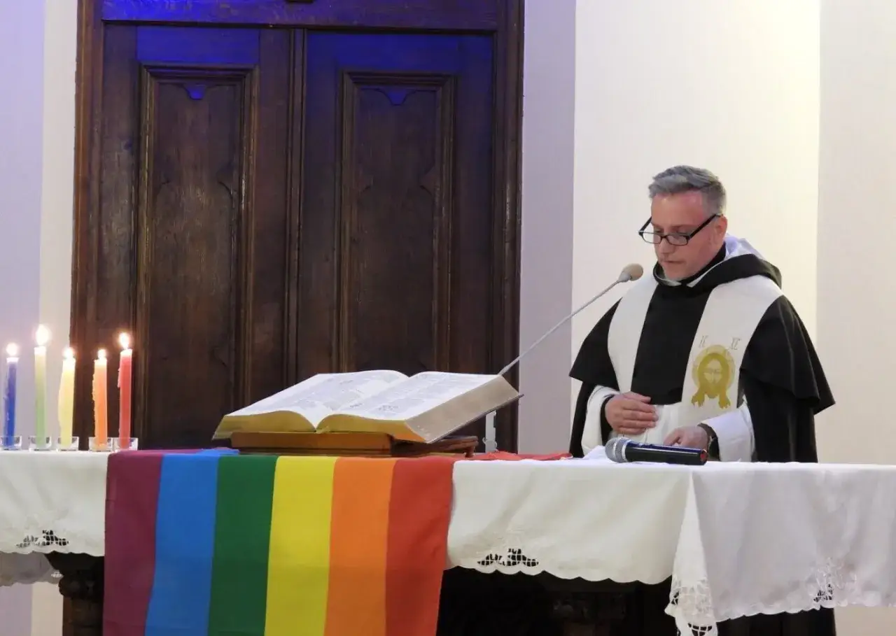 Duchowny z tęczową szatą i Biblią, symbolizujący jak odróżnić wiarę od religijności dylematy współczesnego człowieka.