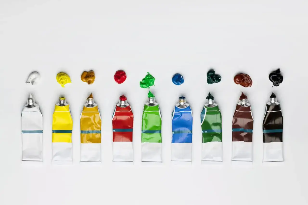 Neuf tubes de peinture de différents types de peinture dessin, avec des gouttes de couleur au-dessus.
