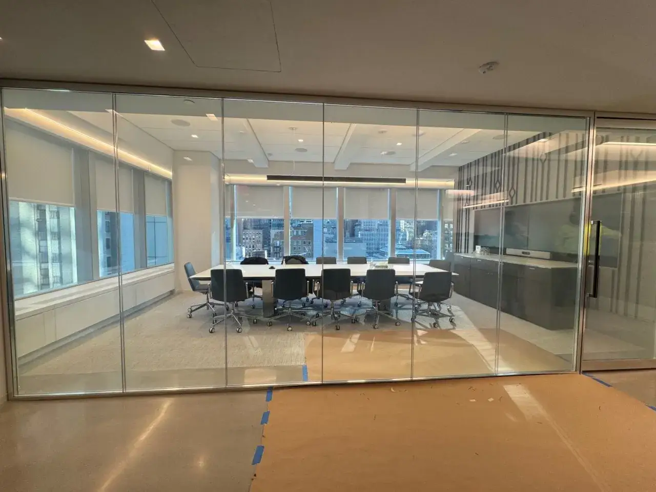 Sala de juntas moderna con mesa y sillas, rodeada por un **cristal que se oscurece** para mayor privacidad.