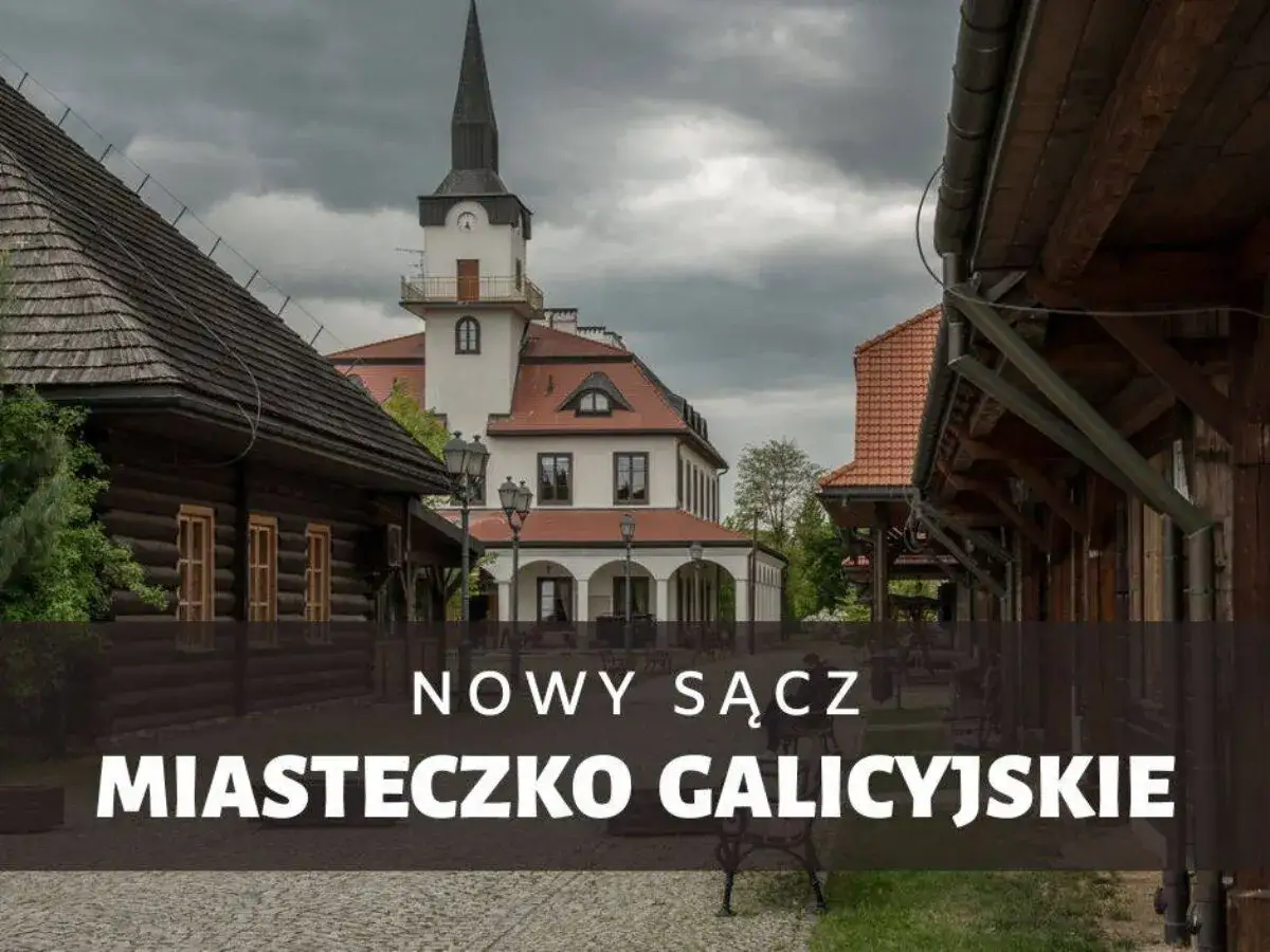Urokliwe miasteczko galicyjskie z drewnianymi domami i wieżą zegarową pod pochmurnym niebem.