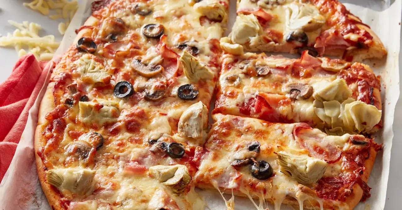 Pyszna pizza capriciosa z kawałkami karczochów, oliwkami i pieczarkami, obficie posypana ciągnącym się serem.