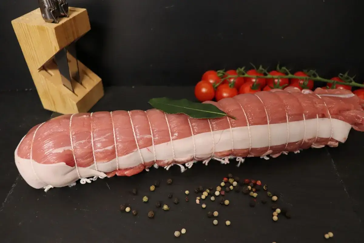 Filet mignon de veau ficel&eacute;, pr&ecirc;t &agrave; &ecirc;tre cuisin&eacute;, avec des tomates cerises et des grains de poivre.