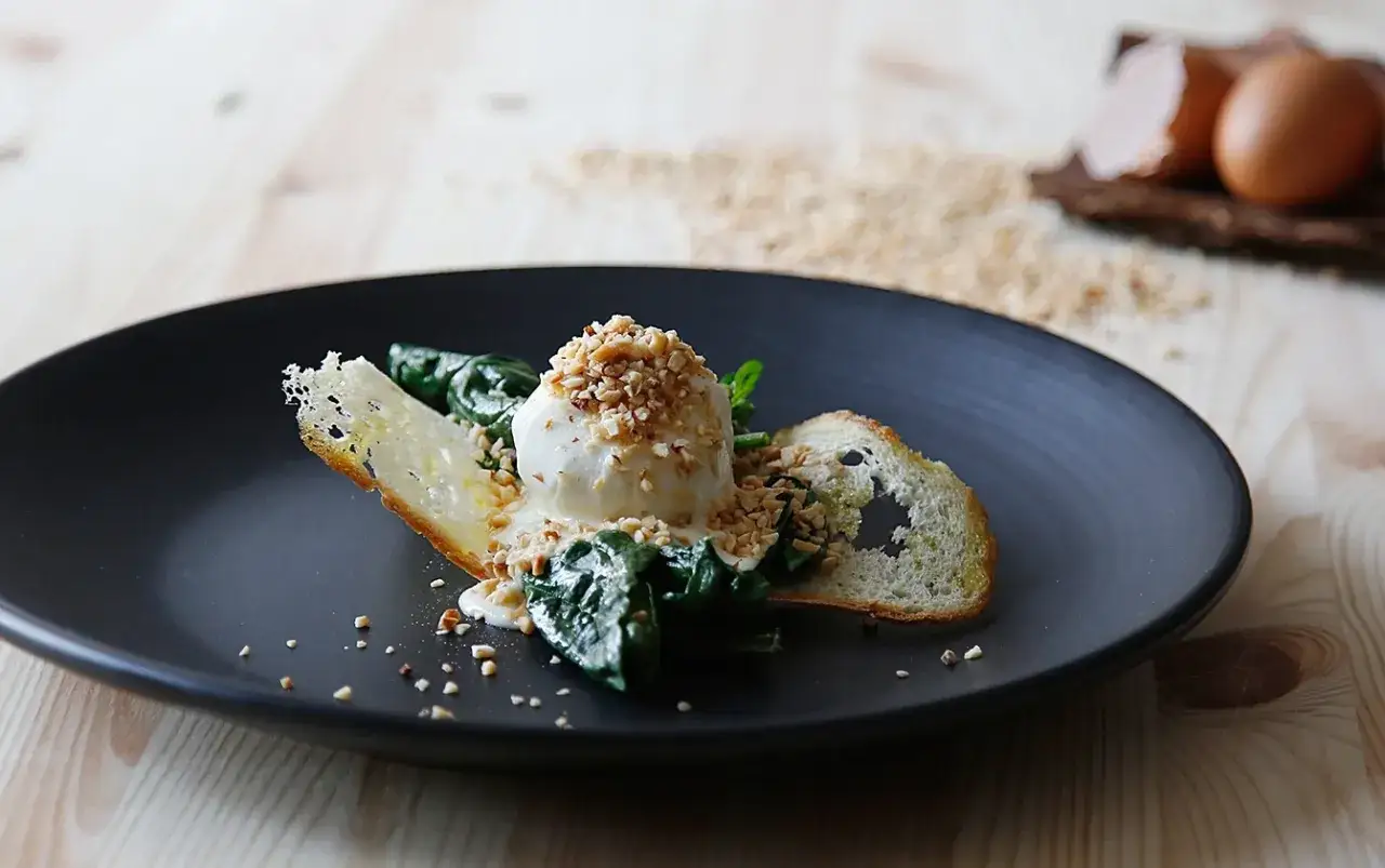 Uovo pochè con fonduta, spinaci e crostini croccanti, guarnito con granella di nocciole.