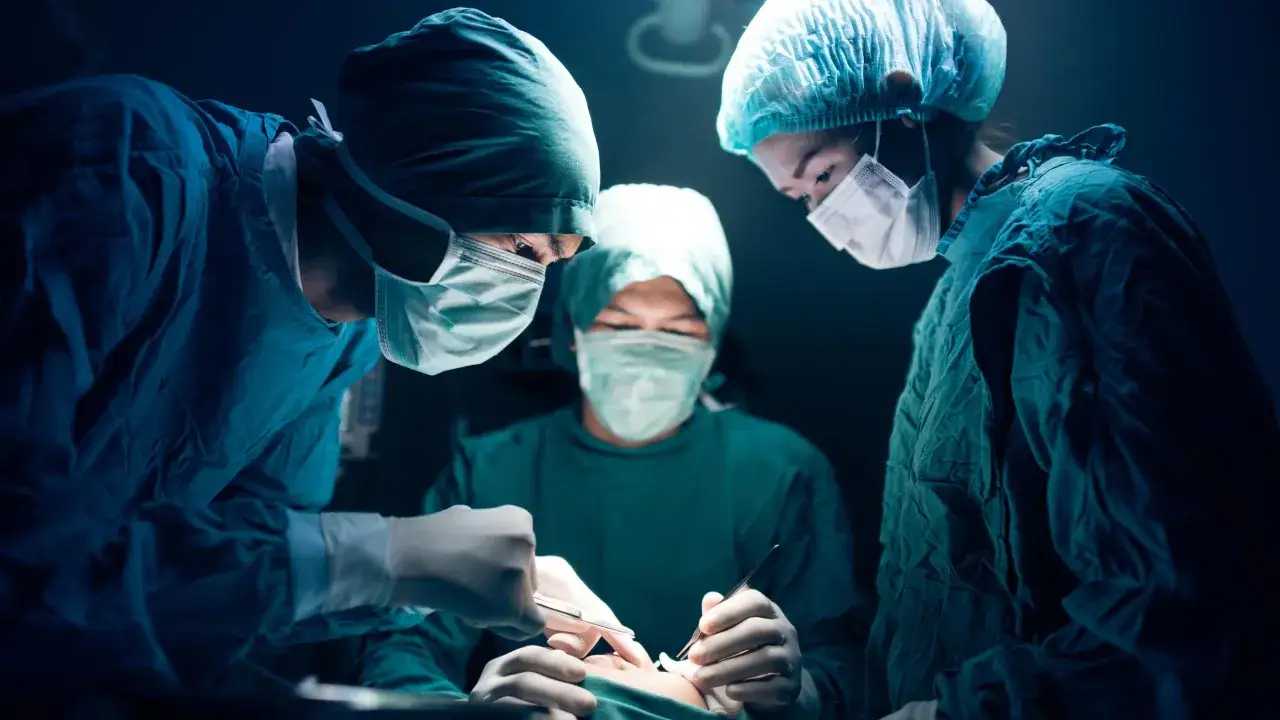 Chirurdzy w maseczkach i czepkach skupieni na operacji. Narkoza skutki uboczne to temat, który budzi niepokój, ale dzięki nim możliwe są ratujące życie zabiegi.