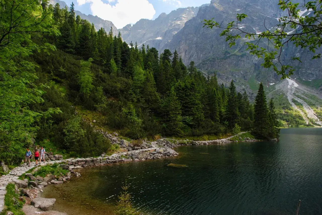 Kamienista ścieżka wije się nad brzegiem jeziora, otoczona lasem. W oddali widać skaliste szczyty. Na jakiej wysokości jest Morskie Oko?
