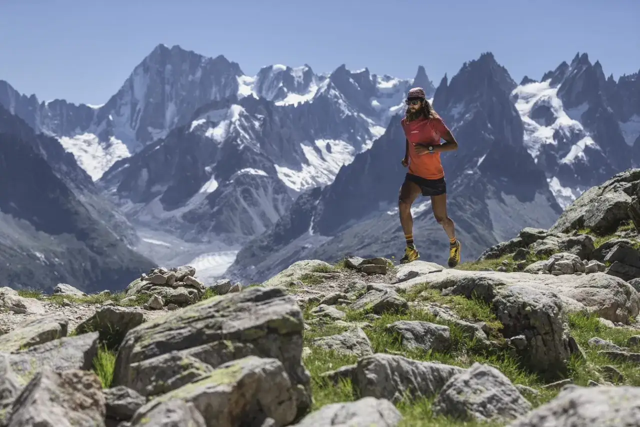 Un coureur en plein effort sur le **trail du Haut Giffre**, avec des montagnes enneig&eacute;es en arri&egrave;re-plan.