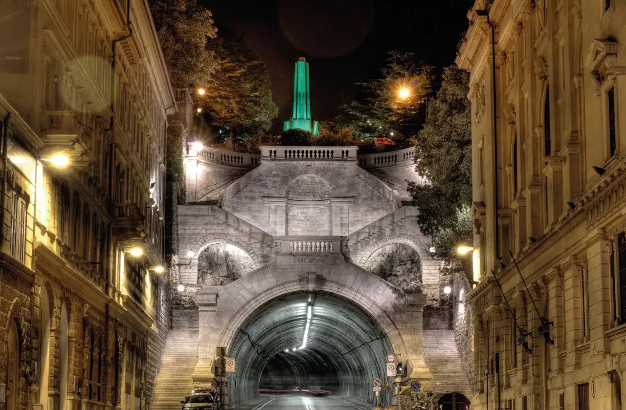 Nocny widok na imponujące schody i tunel w Trieście. Warto zobaczyć ten monument, gdy planujesz, co zwiedzić w Trieście.