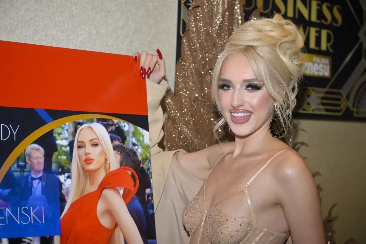 Uśmiechnięta it-girl prezentuje plakat, który może ujawnić prawdę o pochodzeniu majątku rodziny.