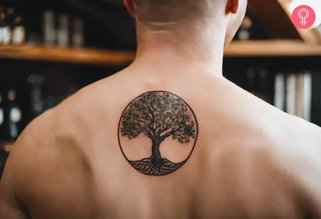 Tatuaż na plecach: symbol odrodzenia, drzewo życia w okręgu. Korzenie sięgają głęboko, gałęzie pną się ku g&oacute;rze, symbolizując ciągłość i nowy początek.