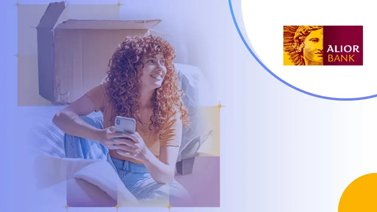 Kobieta z burzą rudych włosów trzyma smartfon, planując przyszłość. Alior Bank pomaga ocenić zdolność kredytową.