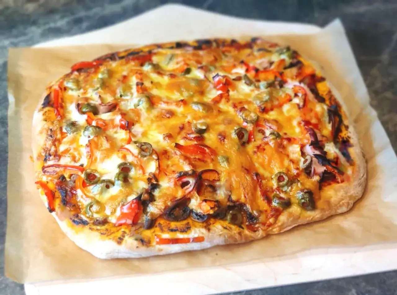 Pyszna pizza z pieczonym czosnkiem, papryką i oliwkami. Idealna do podania z sosem z pieczonego czosnku do pizzy i pieczywa.
