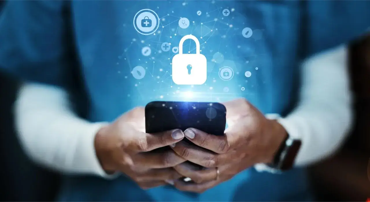 Dłonie trzymające smartfon, nad którym unosi się symbol kłódki i ikony medyczne. Jak sprawdzić czy ktoś ma dostęp do mojego telefonu?