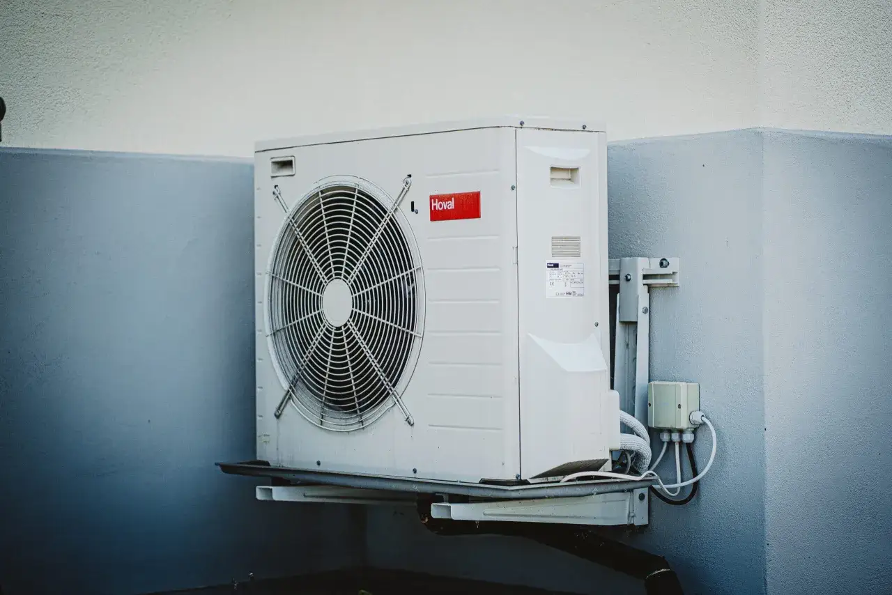 Jednostka zewnętrzna klimatyzatora Hoval z wentylatorem, zamontowana na ścianie. Urządzenie wykorzystuje ekologiczny czynnik R290.
